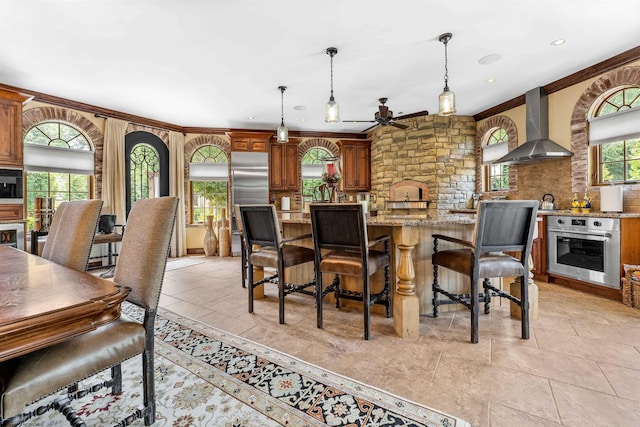 dining room featuring light tile flooring, crown molding, ceiling fan, and a fireplace