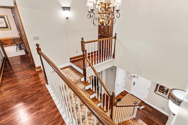 stairway featuring dark hardwood / wood-style flooring, a chandelier, and a towering ceiling