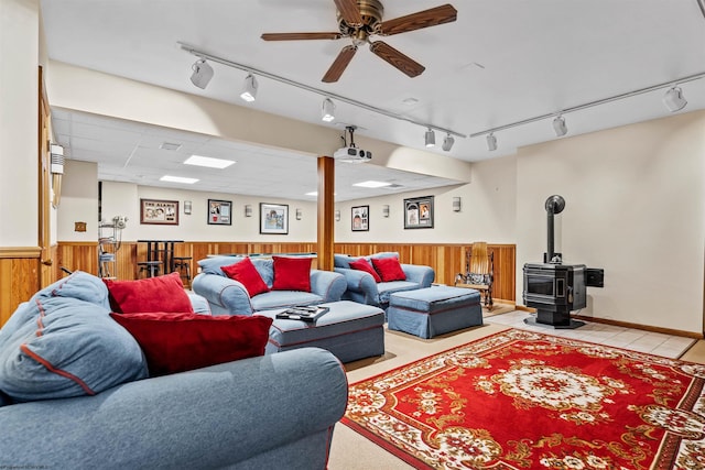 living room featuring ceiling fan, a wood stove, and rail lighting