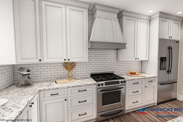 kitchen with backsplash, custom exhaust hood, appliances with stainless steel finishes, and light hardwood / wood-style floors