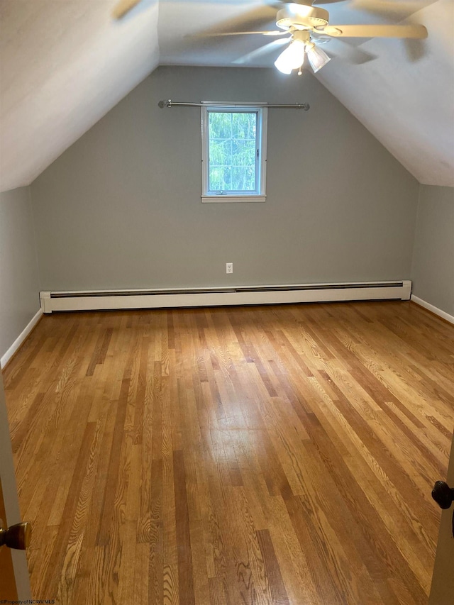 additional living space with ceiling fan, baseboard heating, light wood-type flooring, and vaulted ceiling