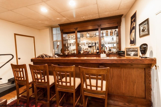 bar featuring wood-type flooring and a paneled ceiling