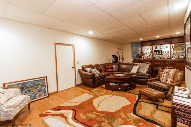 living room with a drop ceiling and light wood-type flooring