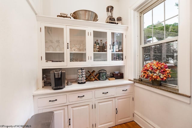 bar with white cabinets and light hardwood / wood-style flooring