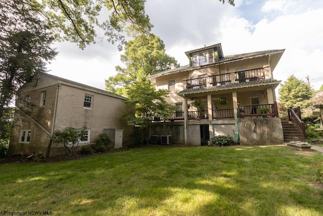 rear view of property featuring a yard, a balcony, and central AC unit