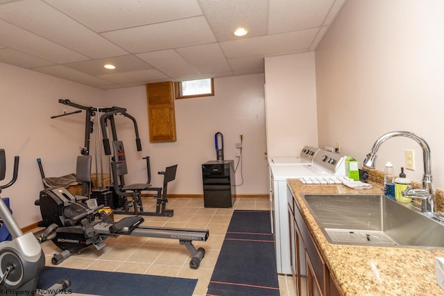 exercise room featuring a drop ceiling, sink, washing machine and dryer, and light tile floors