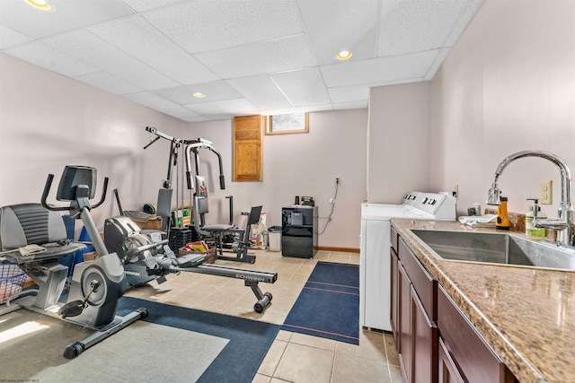 exercise area featuring sink, a paneled ceiling, light tile floors, and separate washer and dryer