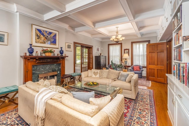 living room with wood-type flooring, beam ceiling, coffered ceiling, a fireplace, and a notable chandelier