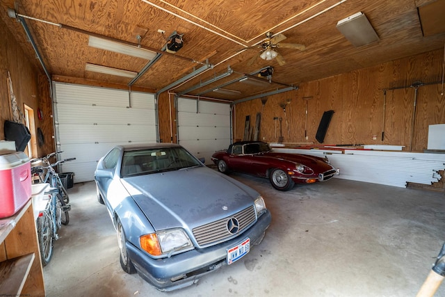 garage featuring ceiling fan and wood walls