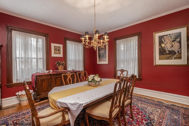 dining space with a chandelier, crown molding, and wood-type flooring