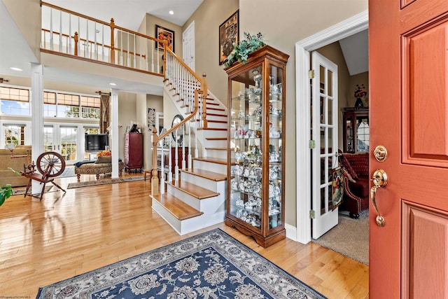 foyer entrance with french doors, high vaulted ceiling, and hardwood / wood-style flooring