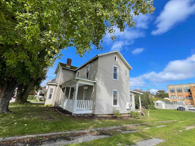 exterior space with covered porch, a yard, and a chimney