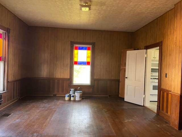 empty room with wood walls and dark hardwood / wood-style flooring