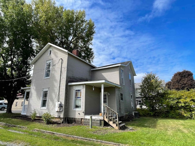 view of front facade with entry steps, a chimney, cooling unit, and a front yard