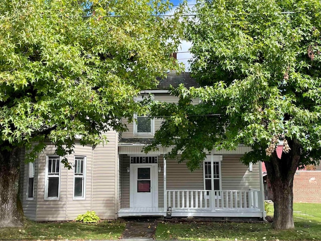 view of property hidden behind natural elements featuring a porch