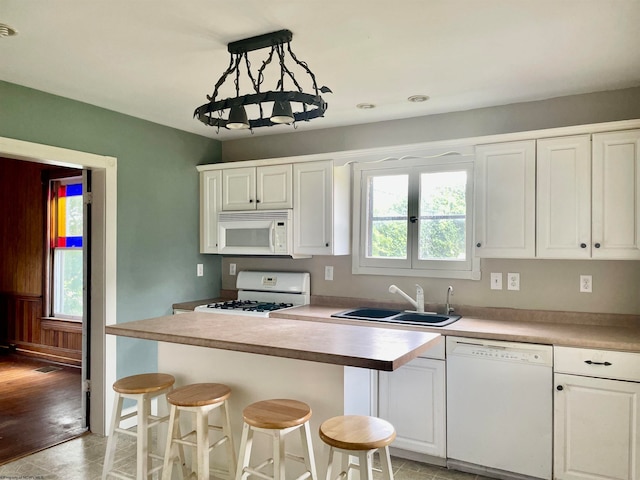 kitchen featuring pendant lighting, white appliances, light hardwood / wood-style floors, and white cabinets