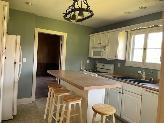 kitchen featuring white appliances, a kitchen island, dark tile patterned flooring, pendant lighting, and sink