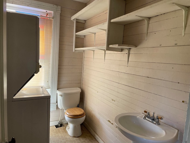 bathroom featuring wooden walls, tile patterned floors, toilet, and vanity