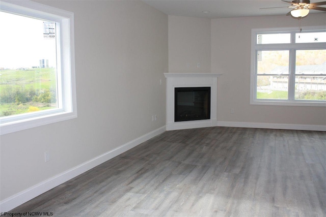 unfurnished living room featuring dark hardwood / wood-style flooring, ceiling fan, and plenty of natural light