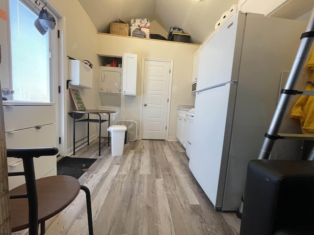 kitchen with white cabinetry, vaulted ceiling, light wood-type flooring, freestanding refrigerator, and stacked washer and clothes dryer