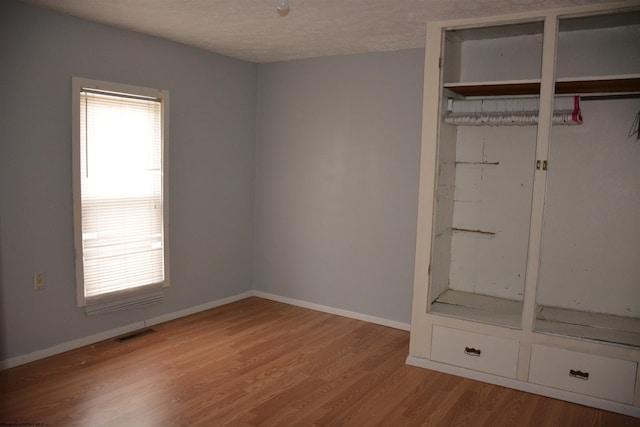 unfurnished bedroom featuring a closet, multiple windows, and light hardwood / wood-style floors