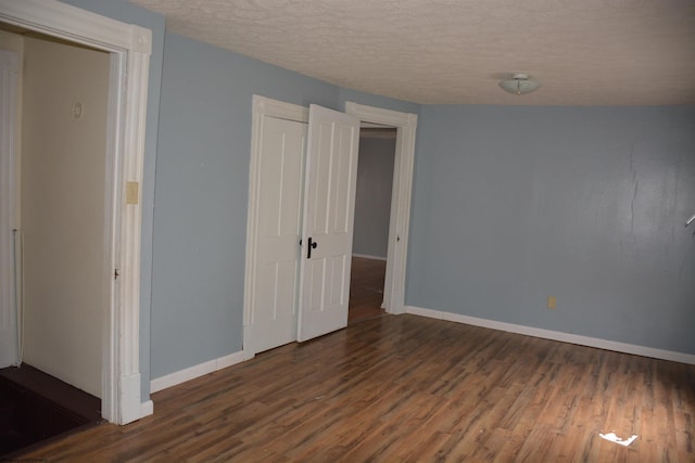 unfurnished bedroom featuring a textured ceiling and dark hardwood / wood-style flooring