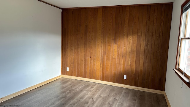 spare room with ornamental molding, hardwood / wood-style floors, and wooden walls