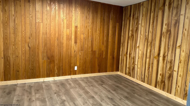 unfurnished room featuring wooden walls and wood-type flooring