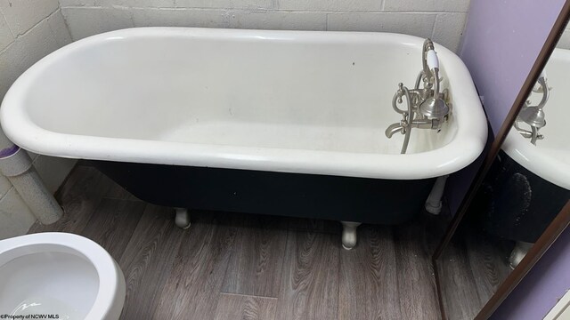 bathroom with a tub, hardwood / wood-style flooring, and toilet