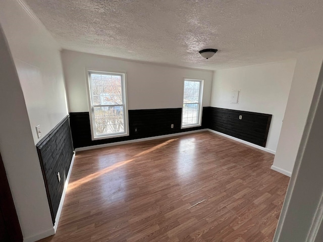 unfurnished living room with wood-type flooring, a textured ceiling, and a healthy amount of sunlight