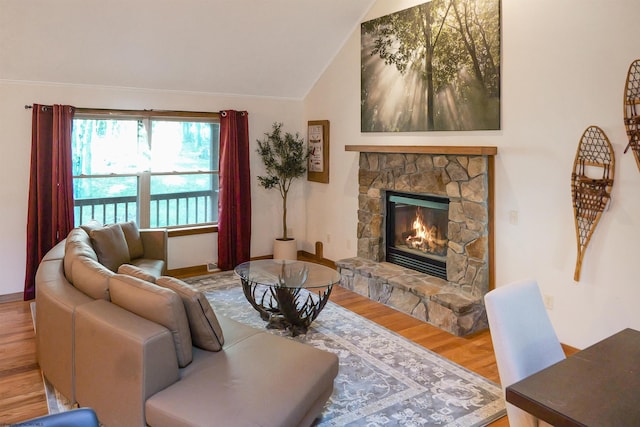 living room with a stone fireplace, wood-type flooring, and vaulted ceiling