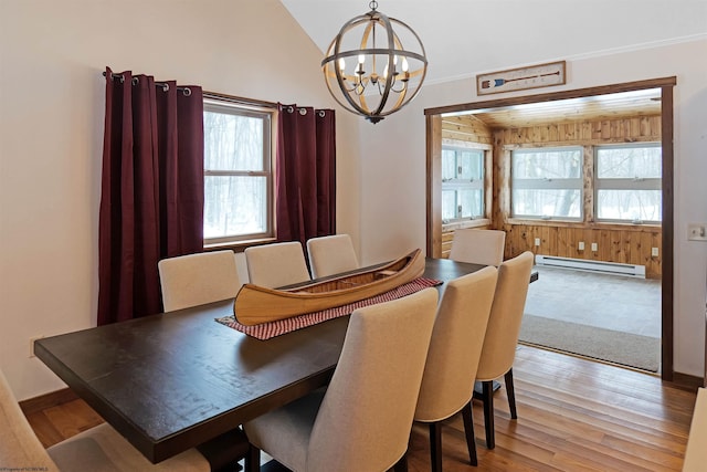 dining area featuring light wood-type flooring, a chandelier, vaulted ceiling, and a baseboard heating unit