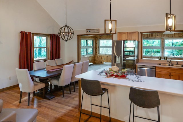 kitchen featuring pendant lighting, lofted ceiling, sink, stainless steel appliances, and light hardwood / wood-style flooring