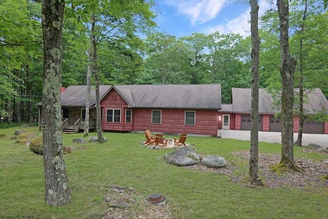 view of front of house with a garage, a front lawn, and a fire pit