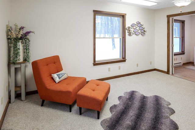 sitting room featuring baseboard heating, light colored carpet, and a wealth of natural light