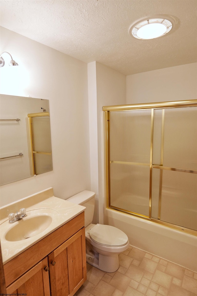 full bathroom featuring bath / shower combo with glass door, vanity, a textured ceiling, and toilet