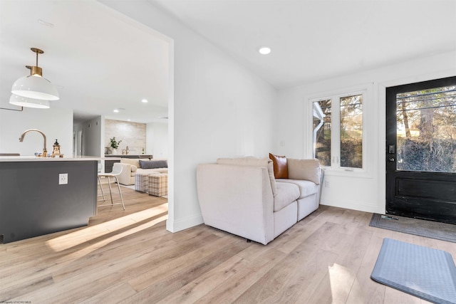 living room featuring vaulted ceiling, sink, and light wood-type flooring