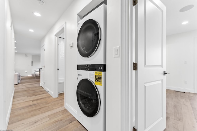 laundry area with light hardwood / wood-style floors and stacked washer / dryer