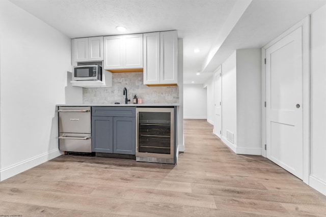 kitchen with gray cabinetry, wine cooler, tasteful backsplash, and light hardwood / wood-style floors