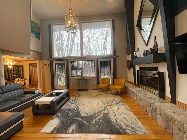 living room with a tiled fireplace, a towering ceiling, and light hardwood / wood-style floors