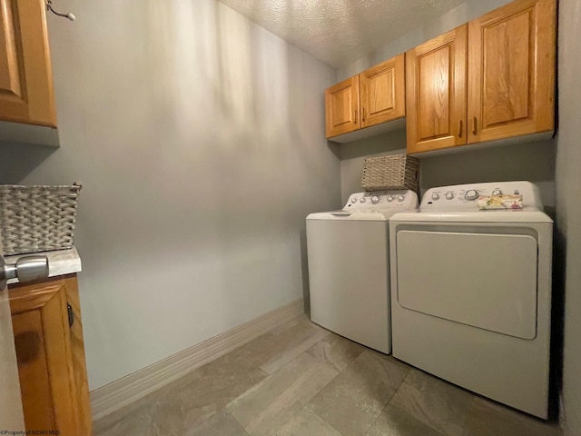 washroom with light tile floors, washing machine and dryer, cabinets, and a textured ceiling