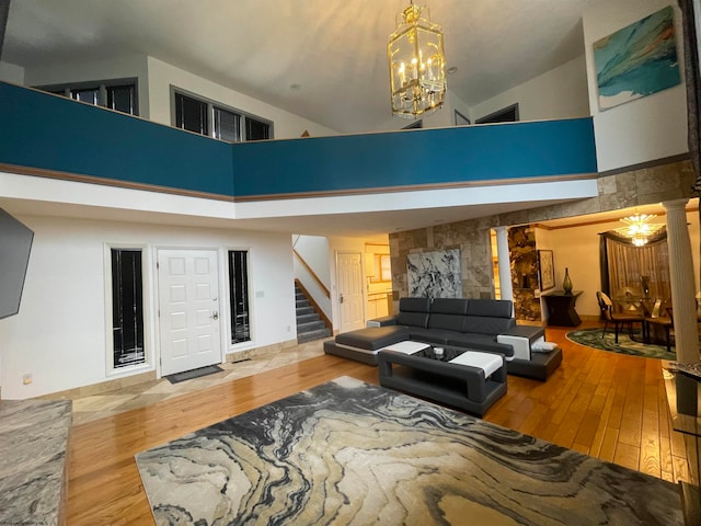 living room with a notable chandelier, high vaulted ceiling, light hardwood / wood-style floors, and ornate columns