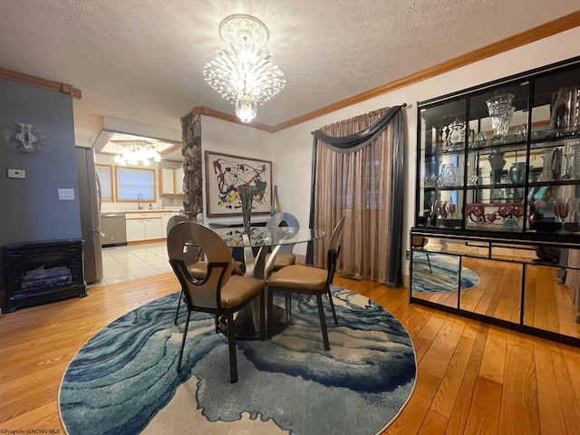 dining room featuring sink, light hardwood / wood-style floors, a chandelier, and a textured ceiling