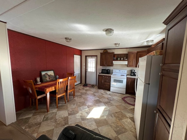 kitchen featuring white appliances, a textured ceiling, and light tile floors