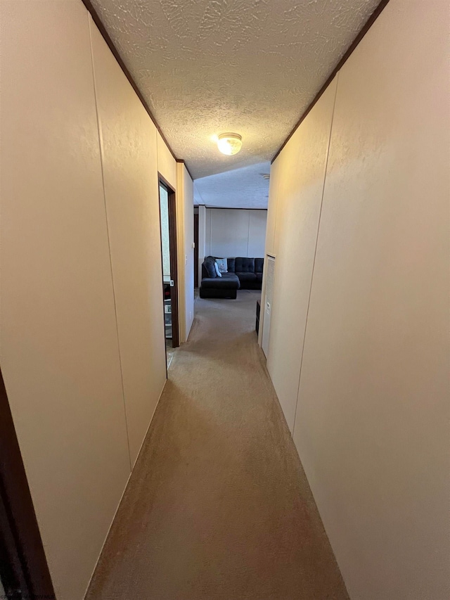 hallway featuring light carpet and a textured ceiling