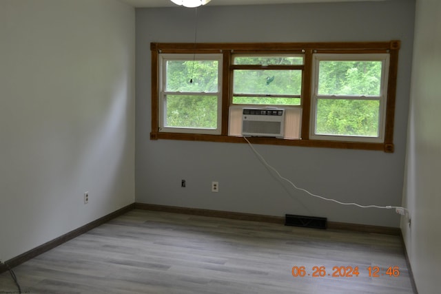 unfurnished room with cooling unit and light wood-type flooring