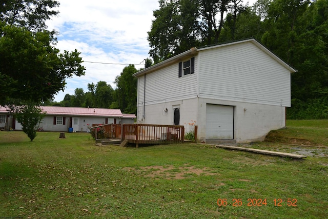 rear view of property featuring a garage, a lawn, and a deck