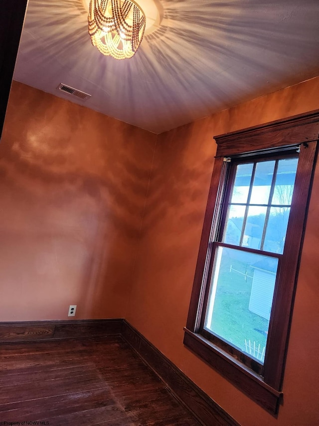 empty room with a notable chandelier and hardwood / wood-style flooring