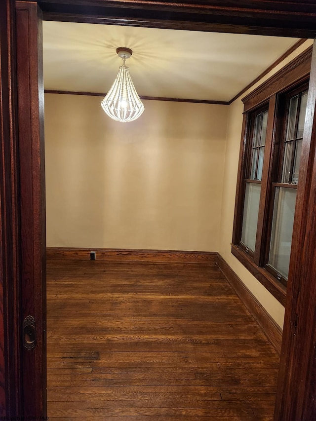 empty room featuring crown molding and dark hardwood / wood-style flooring