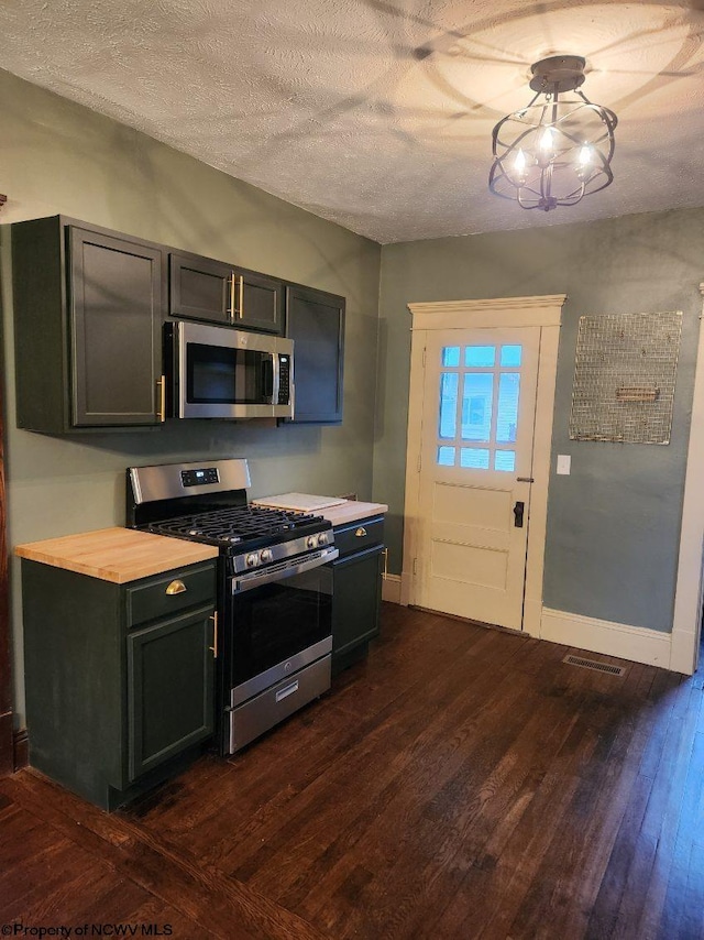 kitchen featuring a textured ceiling, appliances with stainless steel finishes, and dark hardwood / wood-style floors